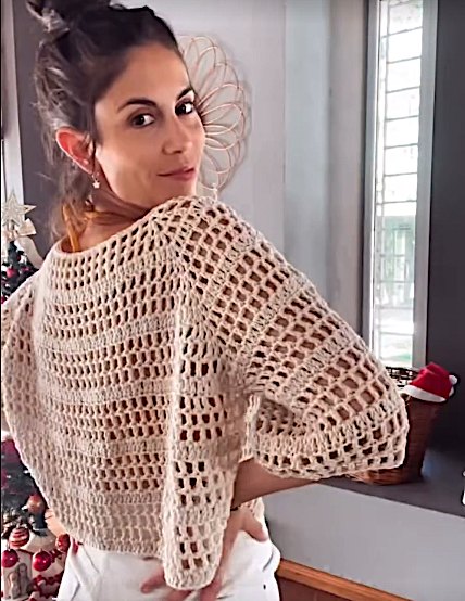 Julieta de espaldas con un suéter calado tejido al crochet en color crudo